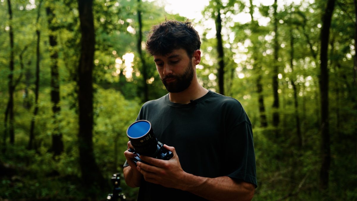Sage Moore holding a cinema camera in a forest.